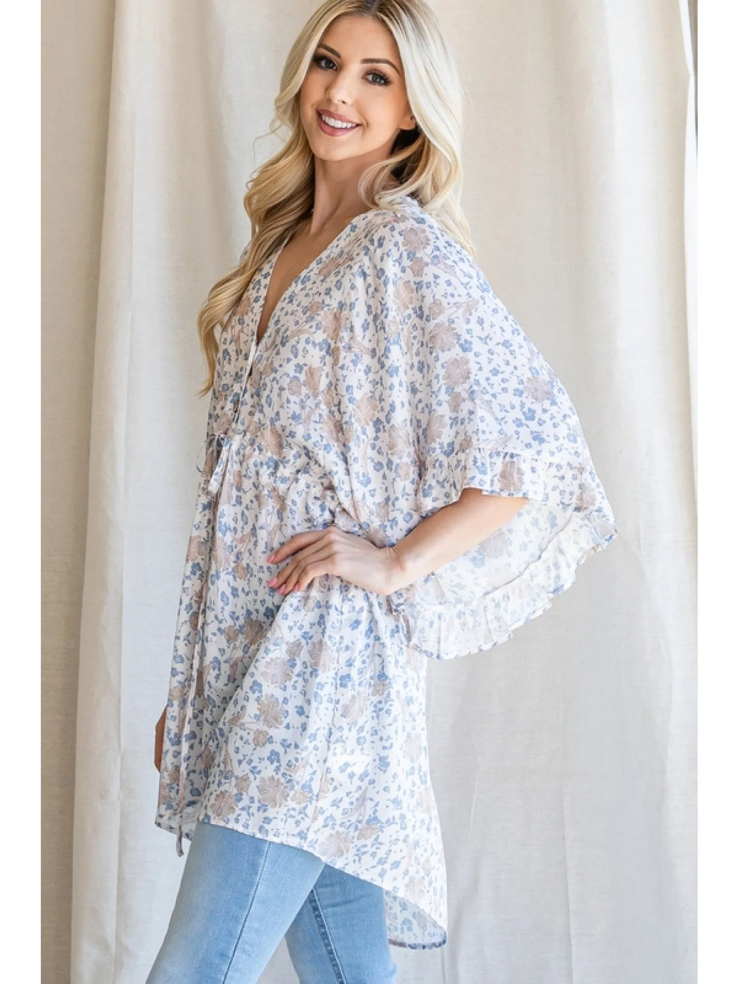 Satin floral print button up tunic with a V-neckline, drawstring waistline, and ruffle trim kimono half sleeve